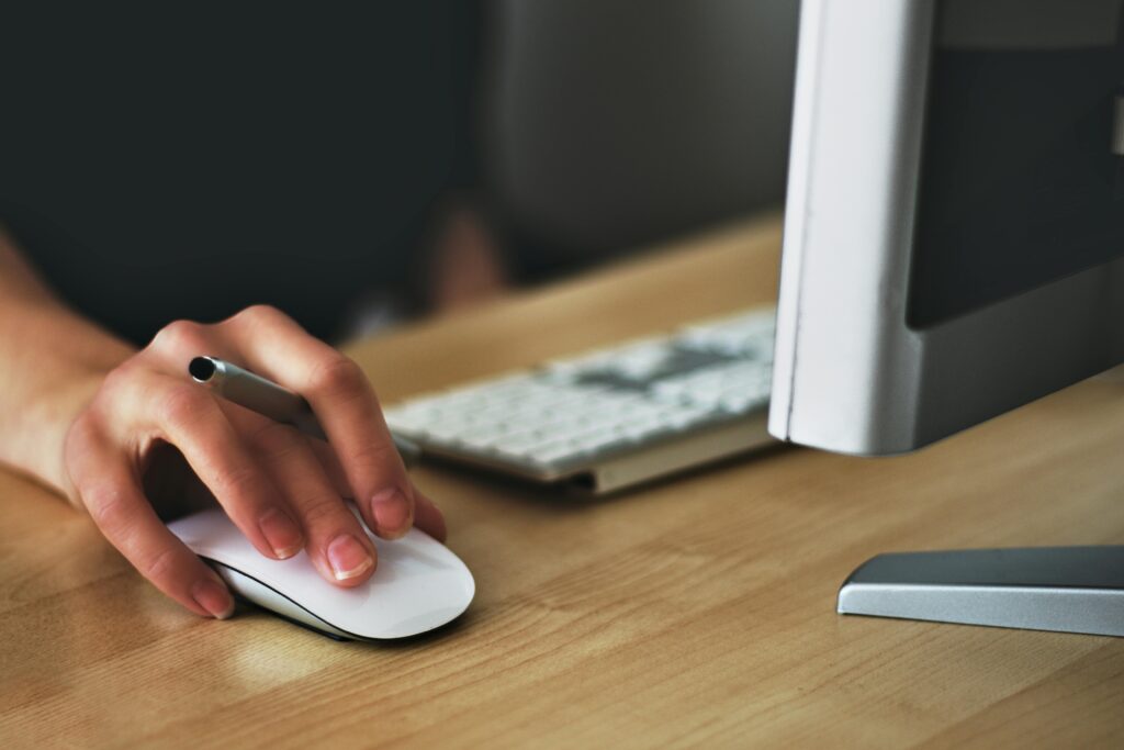 pexels photo 392018 392018 1 A hand using a wireless mouse at a modern desk setup with a computer and keyboard.
