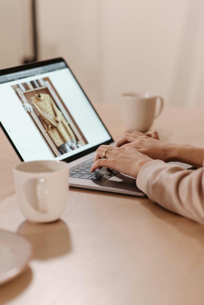 Close-up of hands typing on a laptop in a cozy café setting.